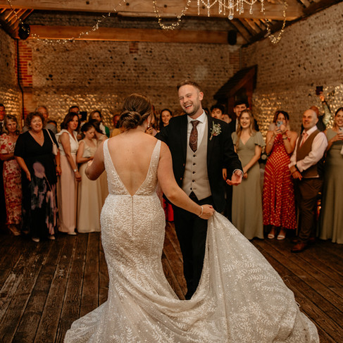 The Bride and Groom's First Dance in the Main Barn with guests watching on.