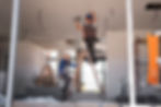 Construction workers installing ceiling fixtures on ladders during an interior build-out – highlighting Local Construction’s skilled crew and commitment to quality on-site execution.