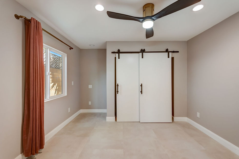 Modern bedroom remodel with double barn doors, ceiling fan, and natural light by Local Constructions in Orange County