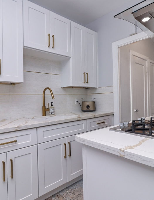 Elegant white kitchen with gold hardware, marble countertops, gas cooktop, and custom cabinetry – a luxury kitchen renovation by Local Construction in Orange County.