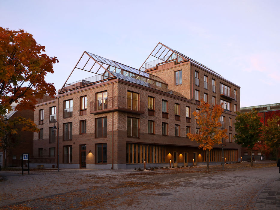 Nyproducerat flerbostadshus i Borås med tegelfasad och växthus på taken.