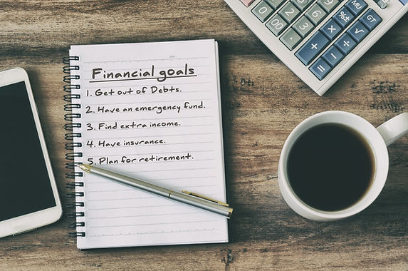 Financial goals on notepad on blank notepad with calculator, coffee, pen and smart phone o