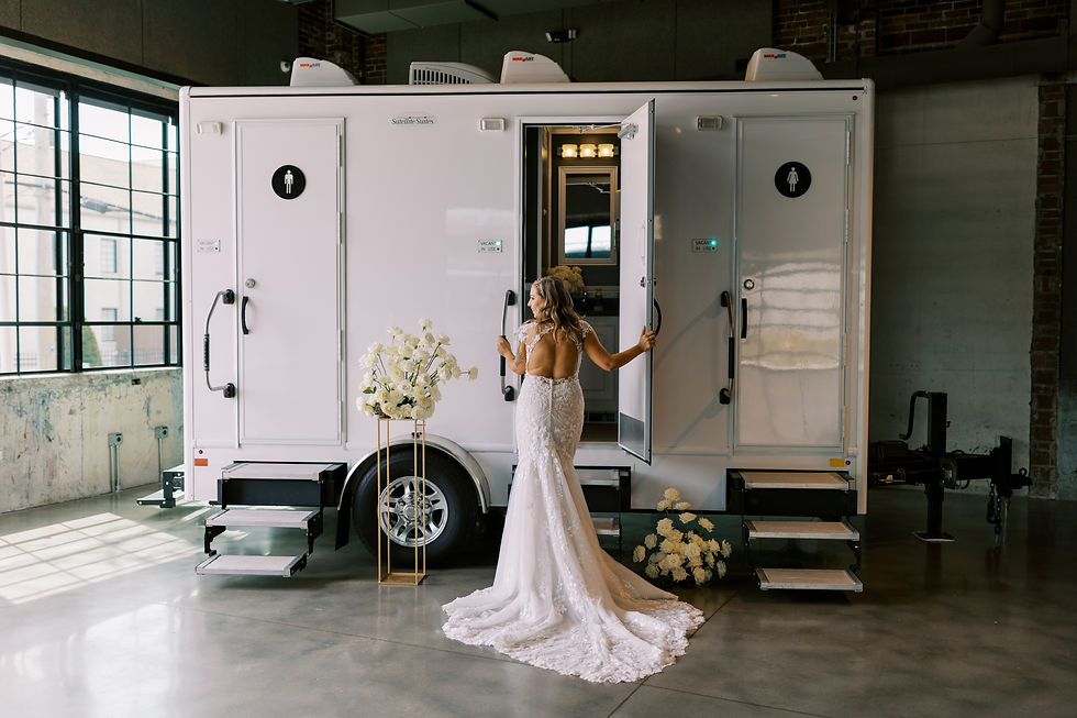 Bride in wedding gown opening the door of a Luxi Loo luxury restroom trailer rental in Northwest Arkansas
