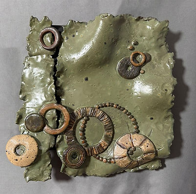sage green stoneware wall sculpture with a cluster of hand-built rings, coils, and disks in tan and bronze glaze, by Shana Or