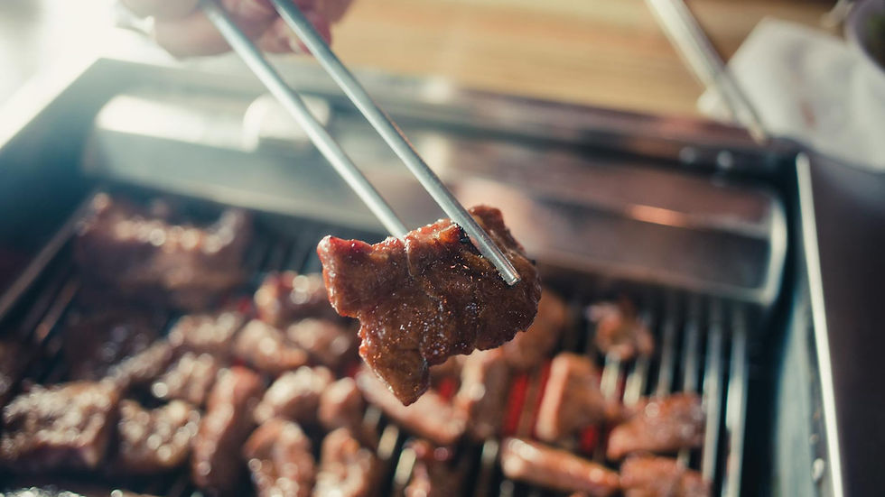 Juicy meat being grilled on a barbecue, captured close-up with chopsticks.