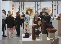 People are in the galley, surrounded with art on the walls and on pedestals.
