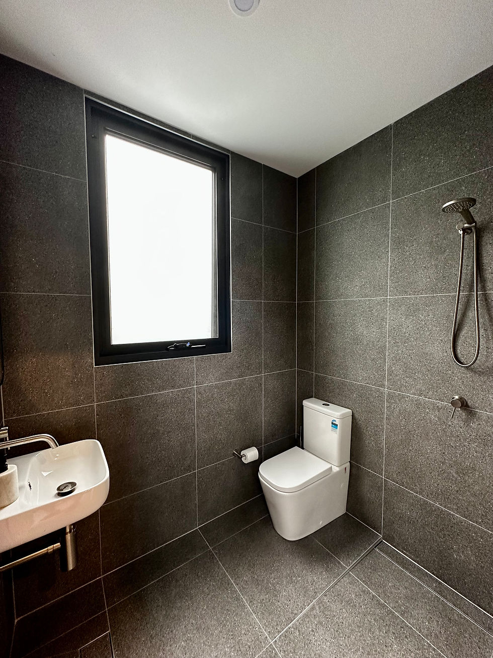 A bathroom with window, sink, toilet bowl and shower