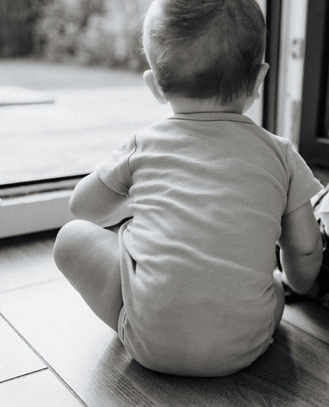 Babyfoto in schwarz/weiss, Baby schaut aus dem Fenster - natürliche Babyfotos in Bad Saarow