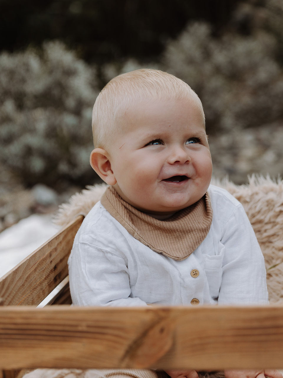 Baby sitzt in einer Kiste und lächelt - liebevolle Babyfotografie in Fürstenwalde