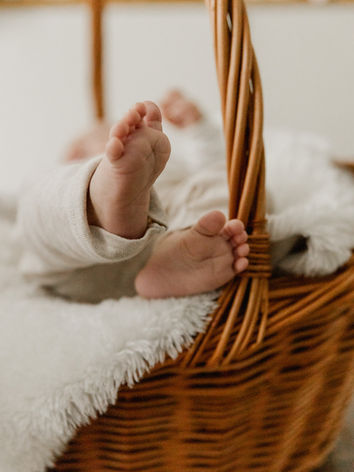 Babyshooting, kleine Babyfüße die aus einem Korb ragen