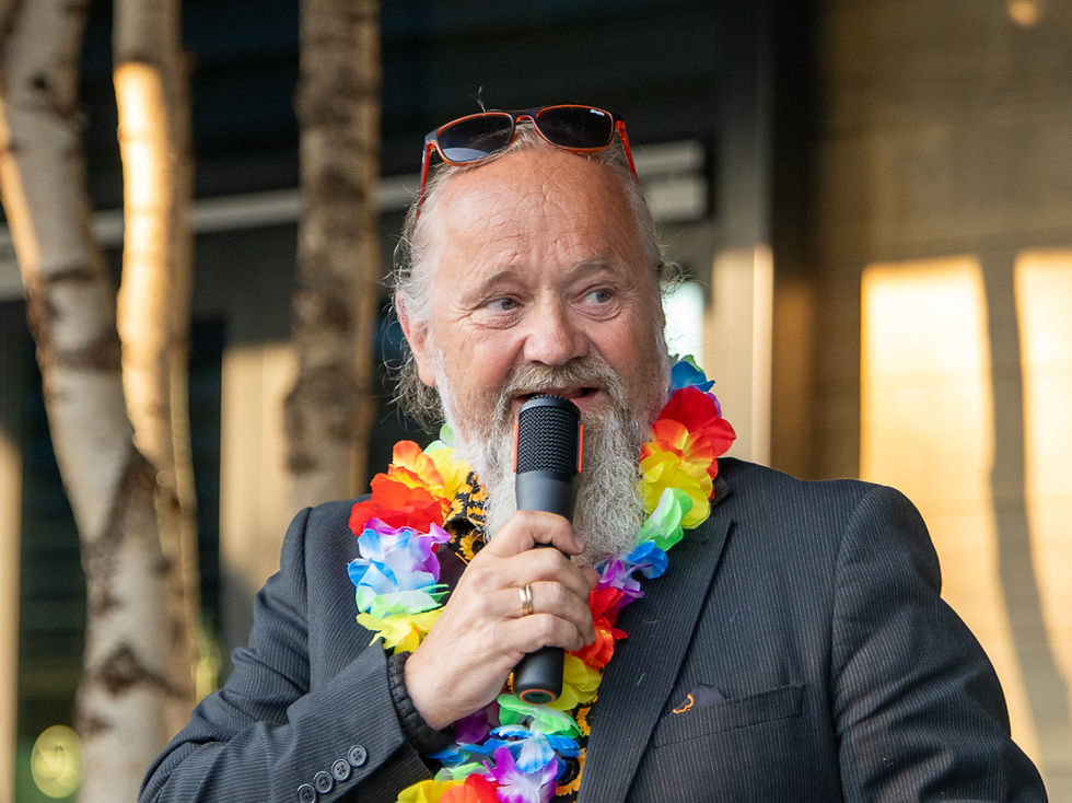 Øyvind ønsker velkommen til sommerfest med en fargerik blomsterkrans om halsen og solbriller på hodet.