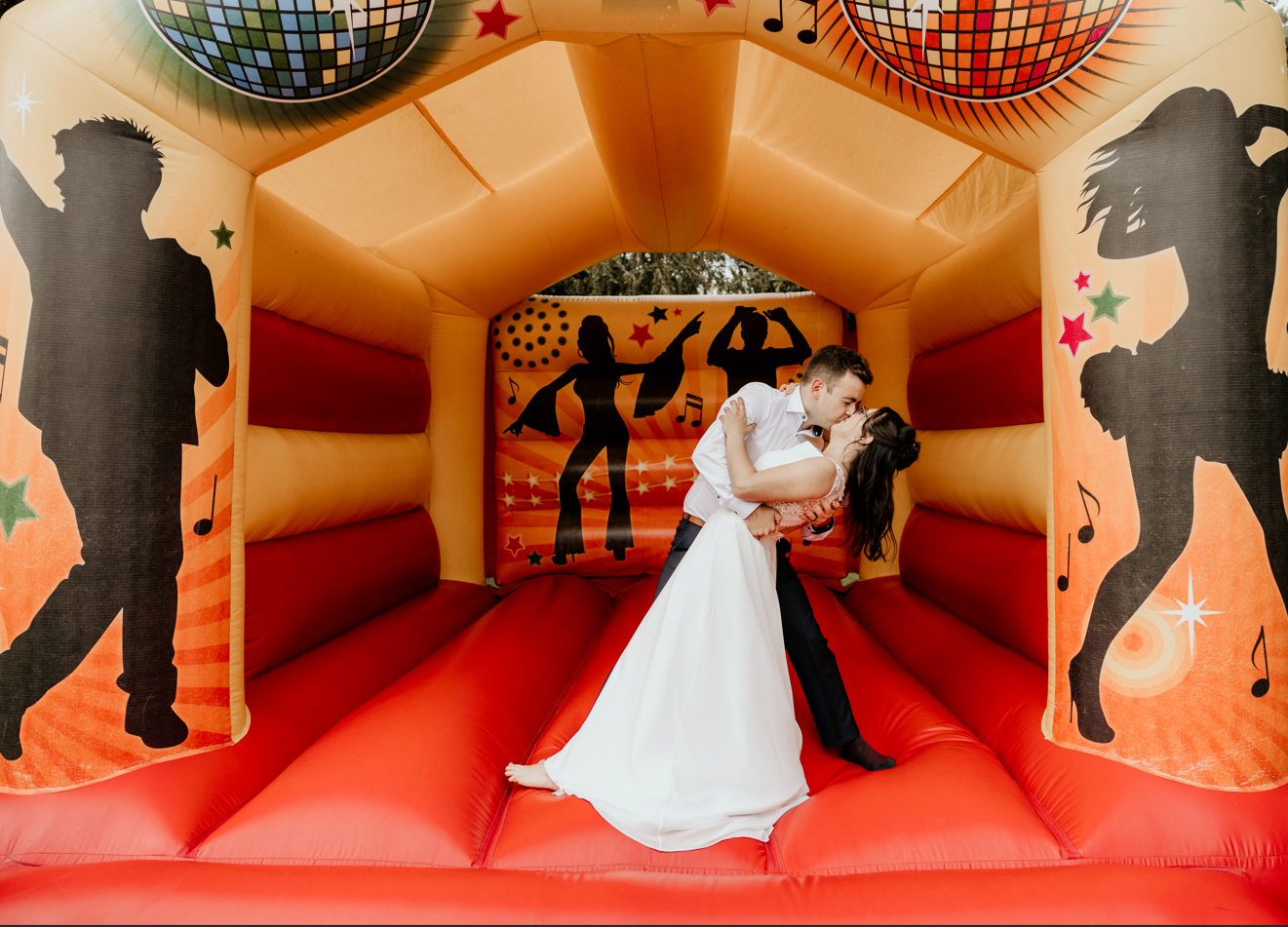 bride and groom kissing whilst stood on bouncy castle