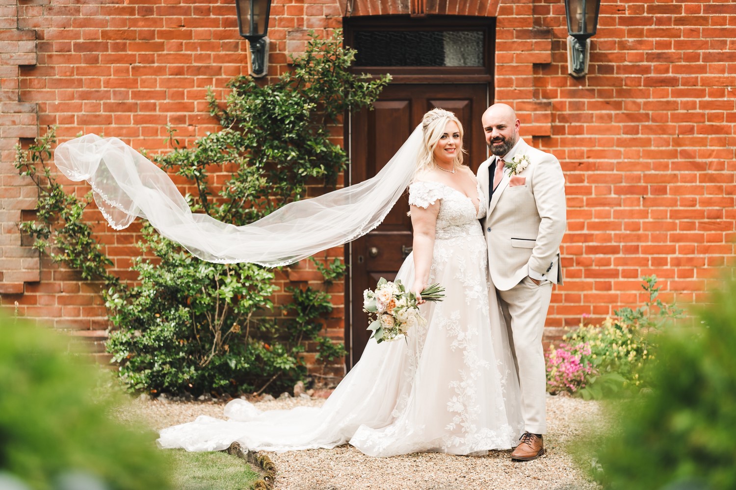 bride and groom stood posed outside of brick building