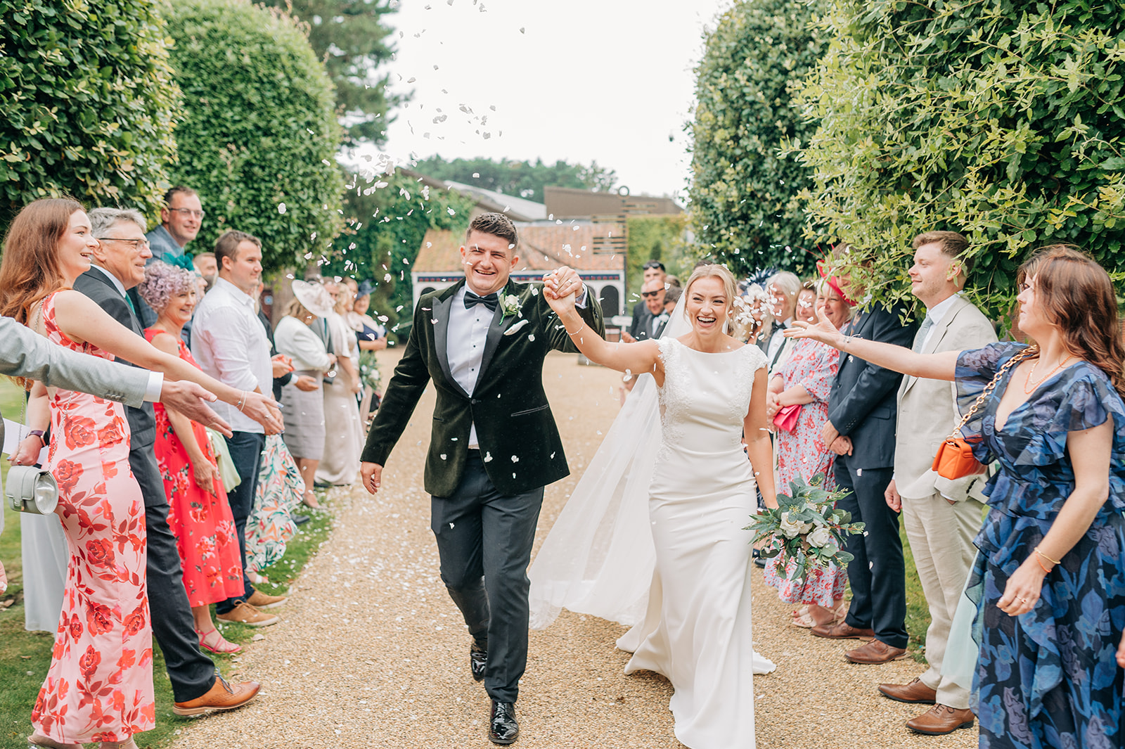 bride and groom walking holding hands past guests throwing confetti