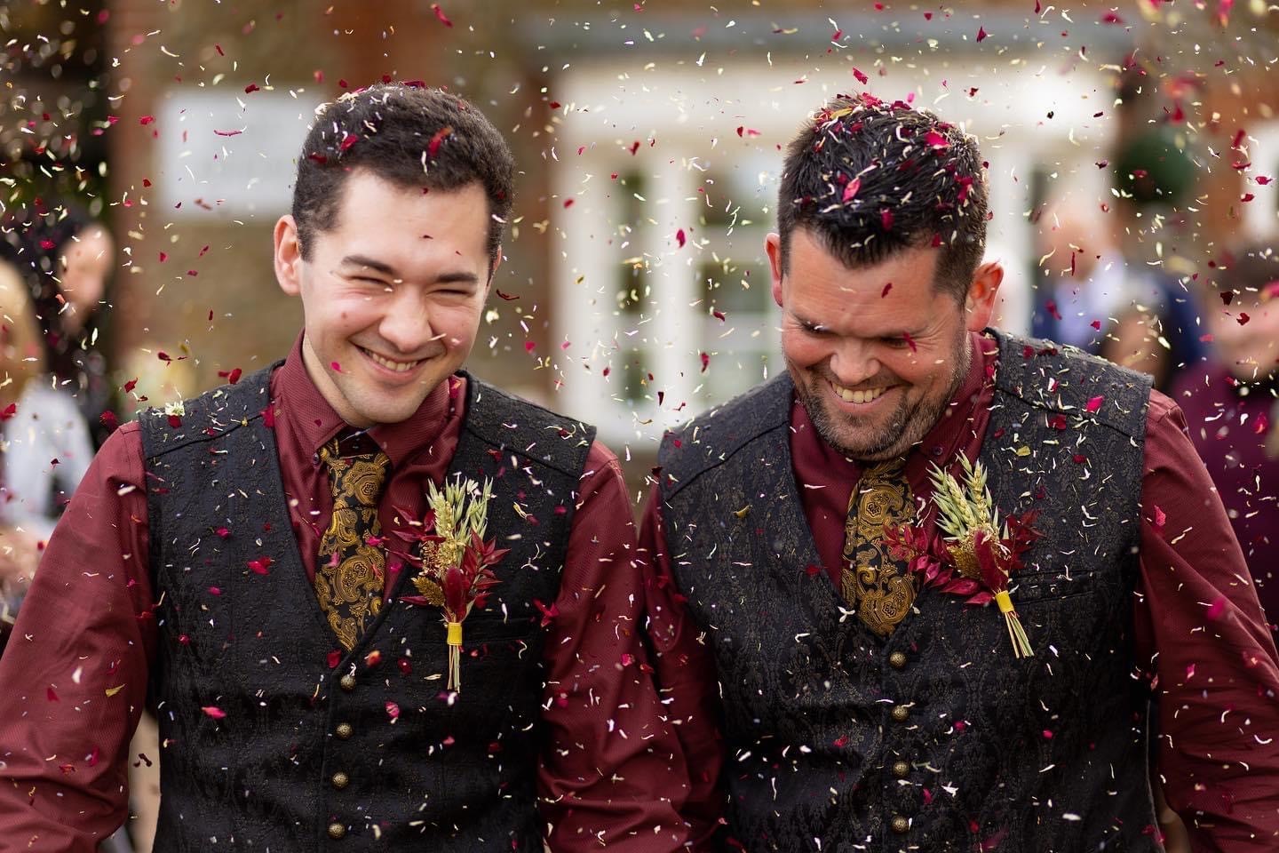 groom and groom smiling outside with confetti being thrown