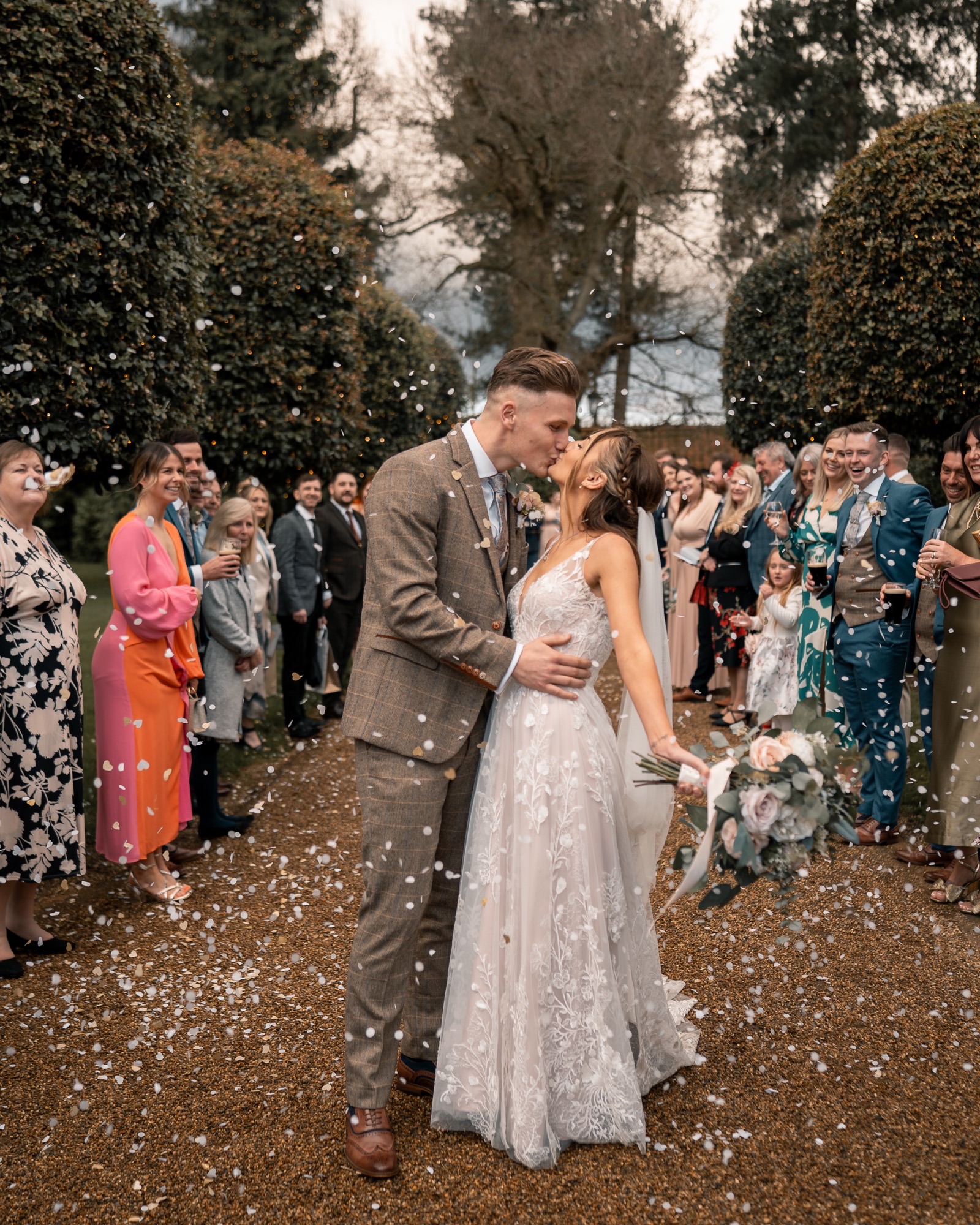 bride and groom kissing in front of guests throwing confetti