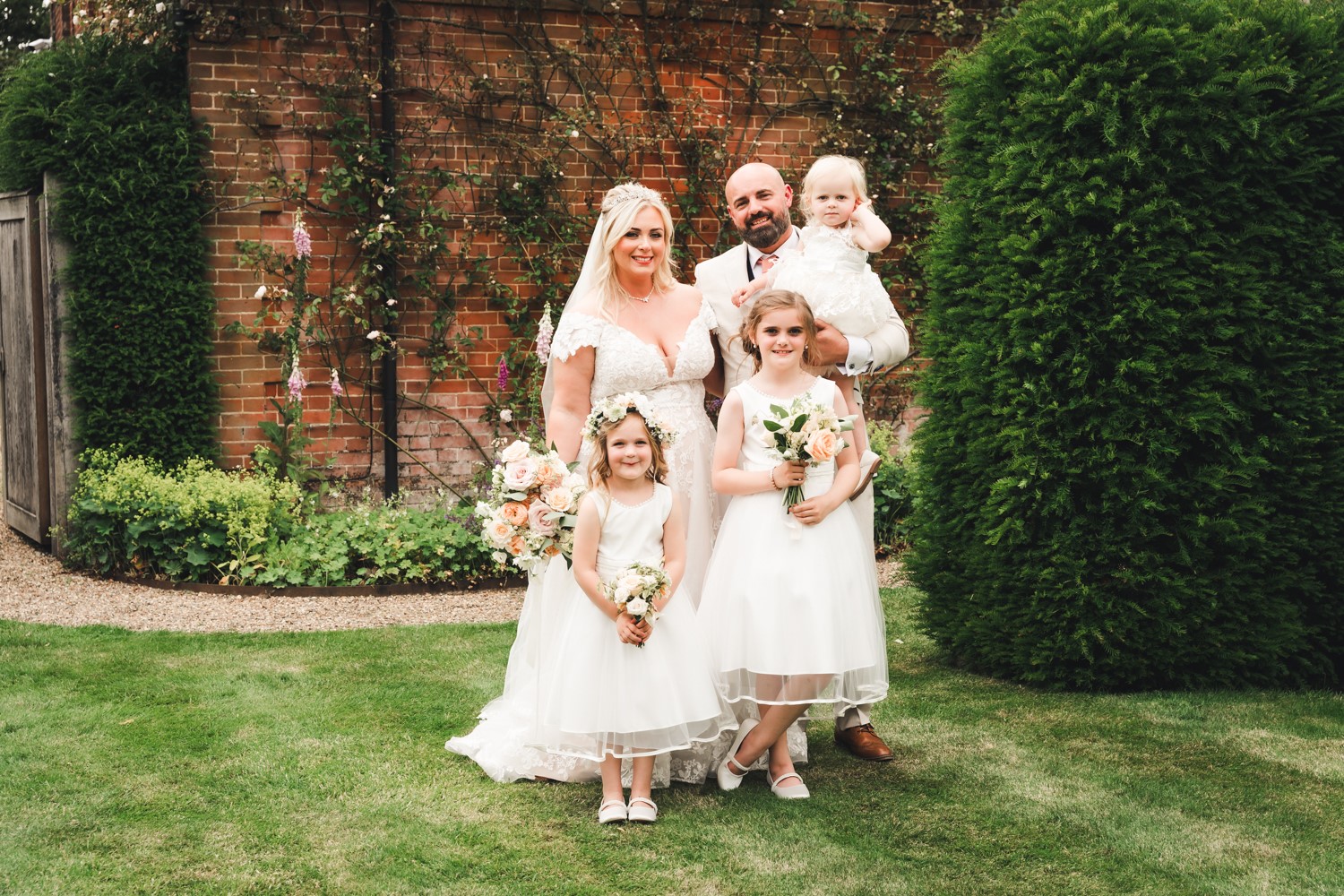 bride, groom and children smiling outside of brick building