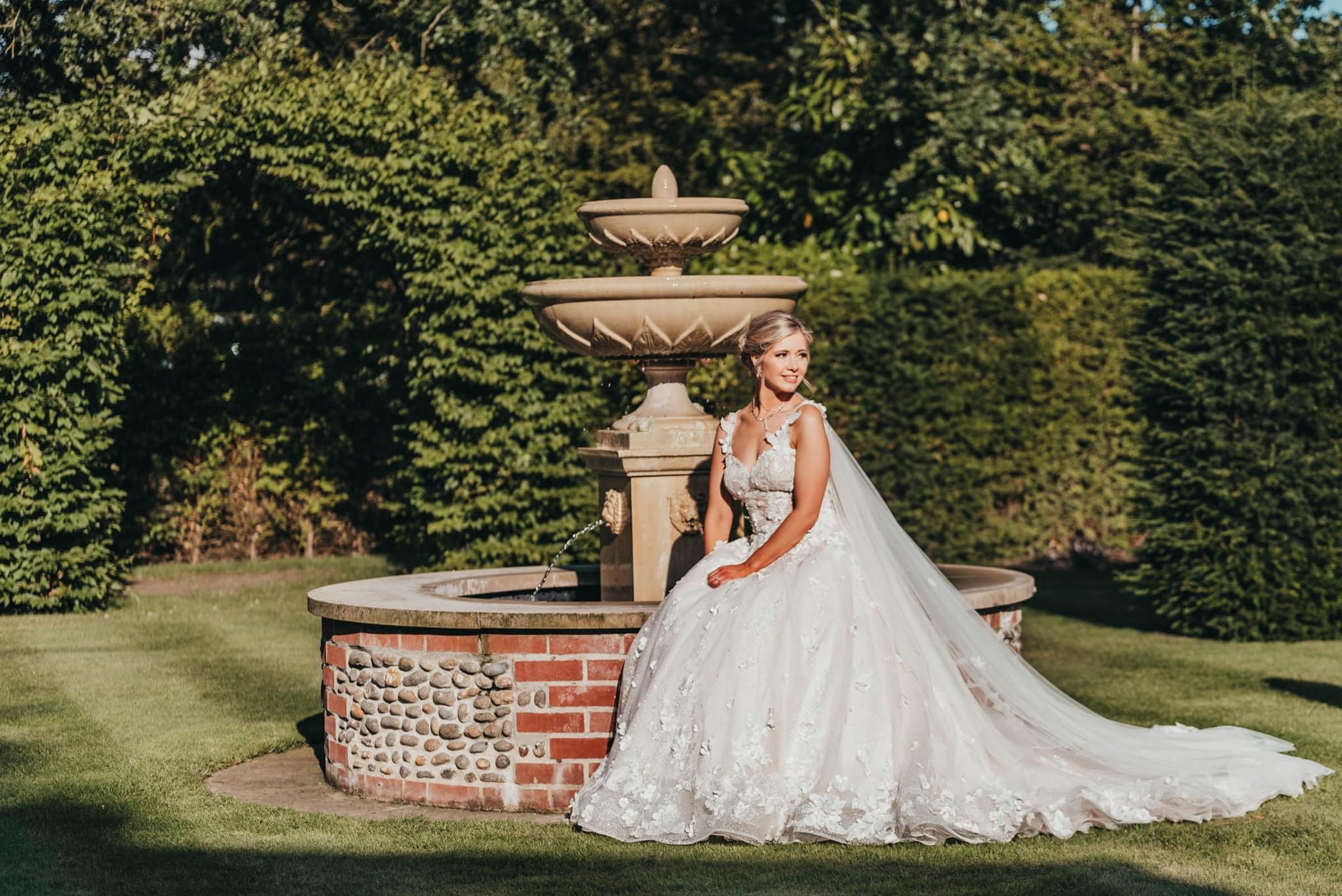 bride sat on edge of water fountain outside