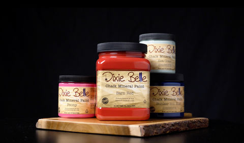 Product display of four Dixie Belle Chalk mineral paint cans of various sizes in dramatic lighting.
