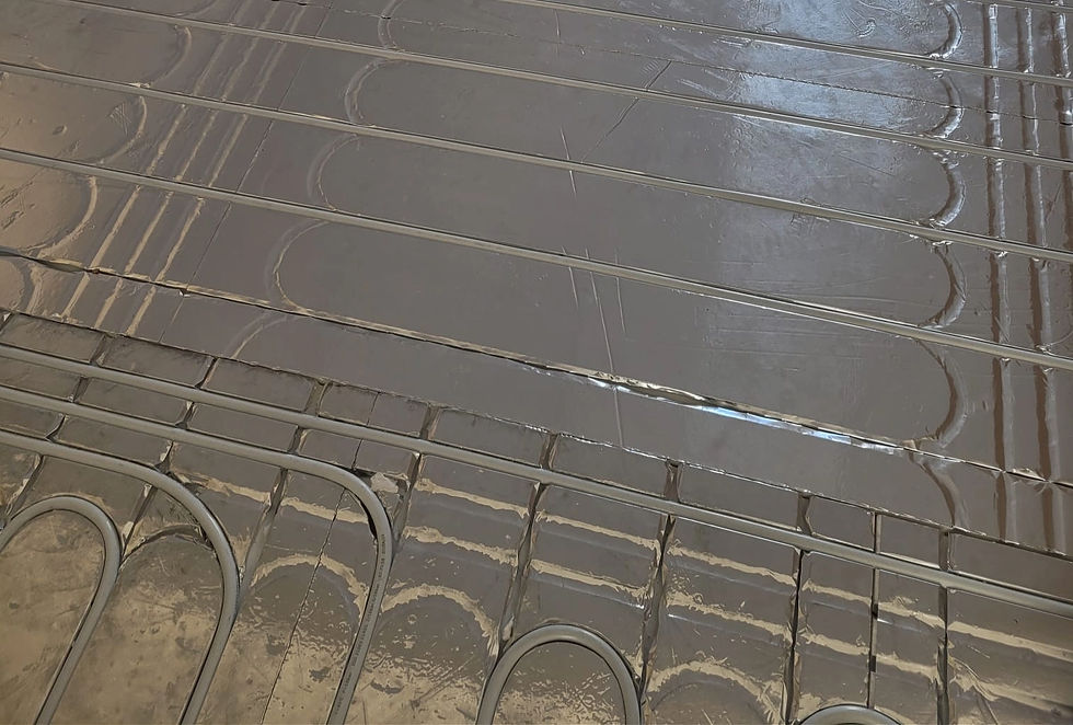 Close-up of a hydronic wet underfloor heating system during installation in a residential property. The image shows water heating pipes laid in continuous loops above a wooden sub base floor layer and reflective insulation panels, designed for energy-efficient radiant heating. Ideal for content related to wet underfloor heating, hydronic heating systems, floor heating installation, sustainable home heating, and modern property renovations in London.