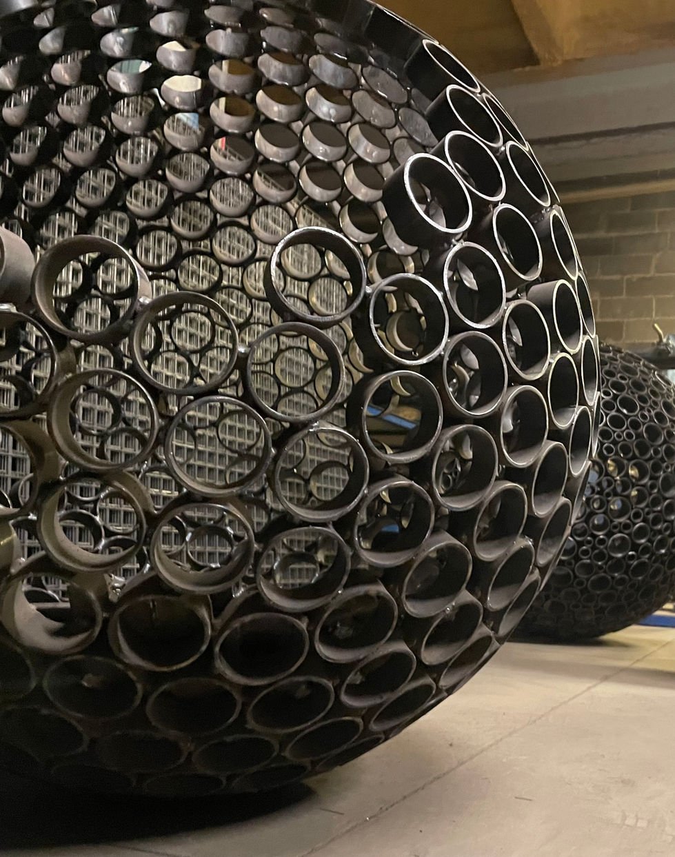 Outdoor metalwork, including large-scale vessels, fire pits, planters, and sculptural objects