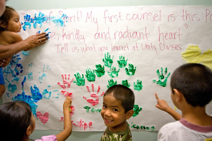 children adding their handprints to a poster about having a kindly and radiant heart
