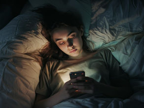 Pessoa usando o celular antes de dormir, ilustrando a hiperestimulação que prejudica o aprendizado.