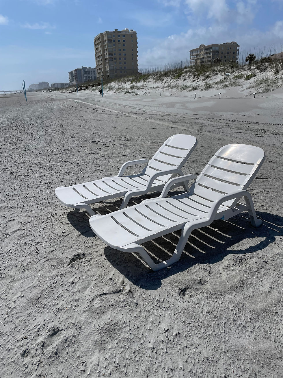 White beach lounge chairs set up on the sand in Jacksonville Beach, FL with ocean view, perfect for