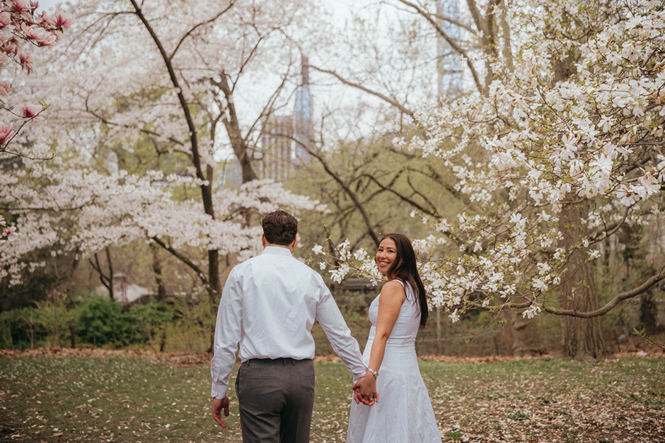 a couple taking photos with the cherry blossoms in new york