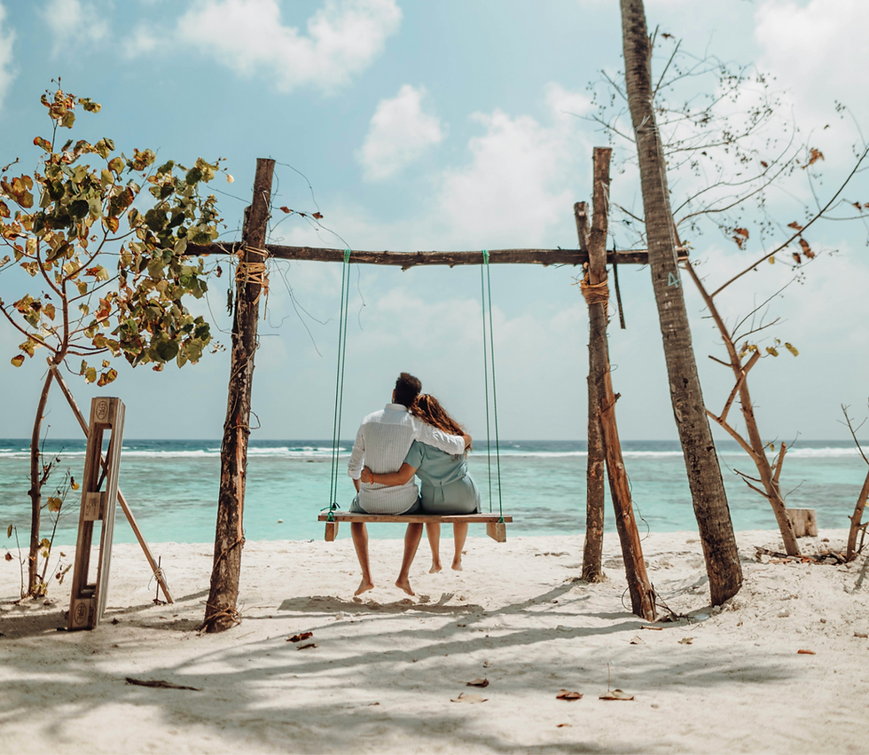 Couple sitting on swing on the beach at their all inclusive honeymoon.