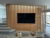 Wall-mounted TV on a modern wooden slat divider.