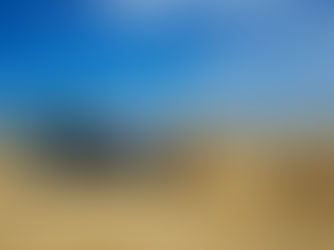 A blue tractor in a field carrying bales of hay