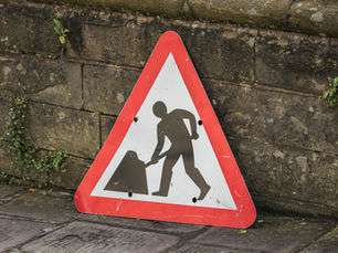 Construction sign leaning against a stone wall