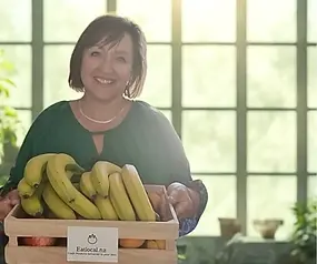 Joanne Webb from Eatlocal holding a crate of fresh, seasonal fruit for your office