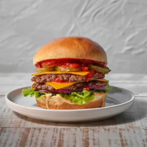 A brioche bun filled with burger patties and salad on a white plate