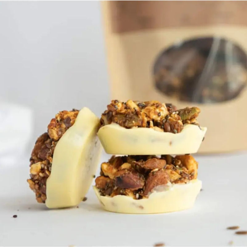 Three caramelised roasted nut and seed clusters coated in a creamy white chocolate base