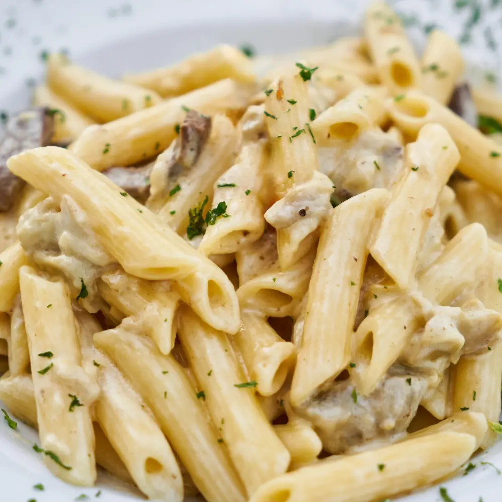 A plate of pasta in a creamy sauce with a sprinkle of chopped parsley
