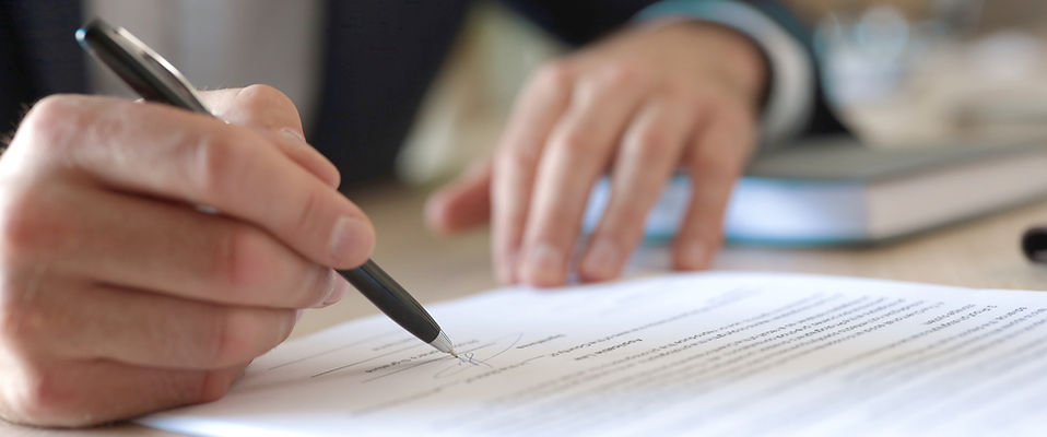 close up of hand signing a document
