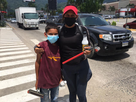 El arduo trabajo de una joven madre e hijo: limpiar vidrios de carro