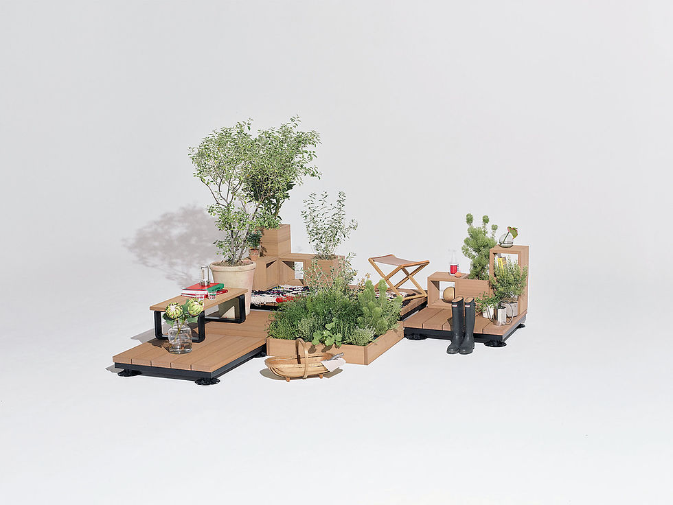 白い背景に、木製の台と箱に観葉植物やハーブ、花瓶、ブーツ、小物を並べた静かなインテリア展示。