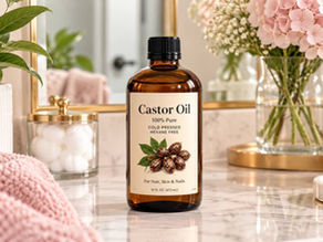 Bottle of pure castor oil on a feminine bathroom countertop with pink flowers and beauty essentials.
