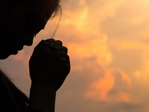 a woman praying with sunset in the back