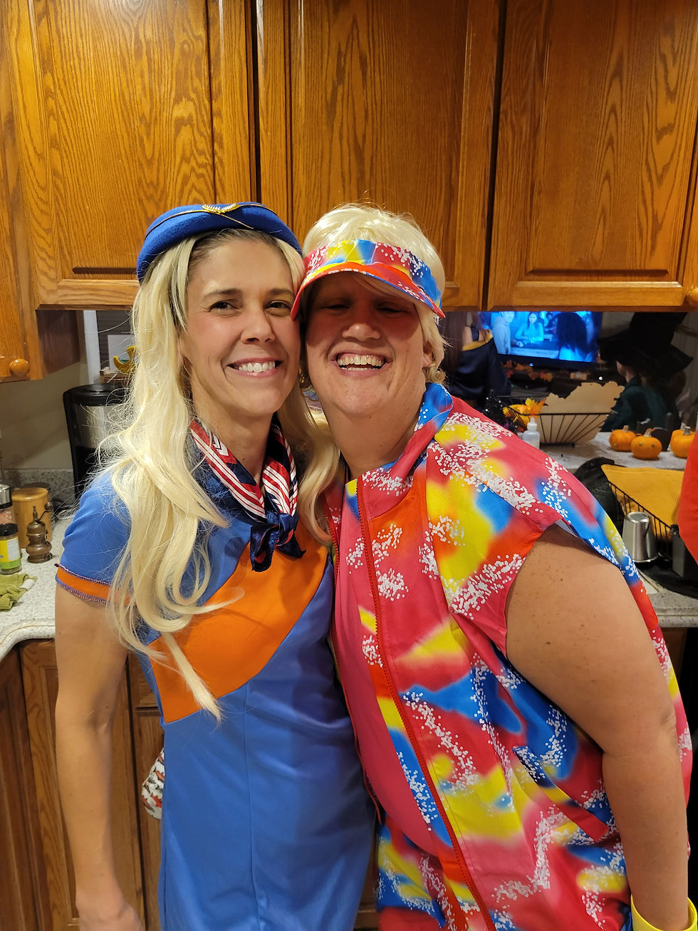 2 Women dressed in Halloween costumes smiling and posing in a kitchen