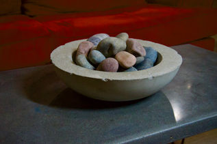 A minimalist concrete bowl filled with decorative stones