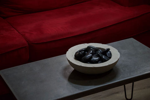 A minimalist concrete coffee table and bowl filled with decorative stones