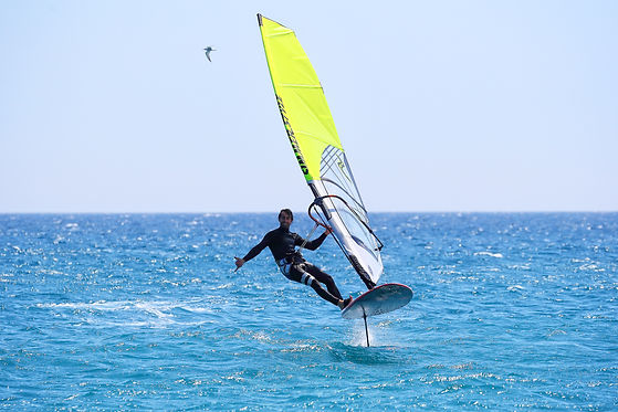 istruttore andrea franchini che naviga volando sul windsurf foil e salutando con una mano