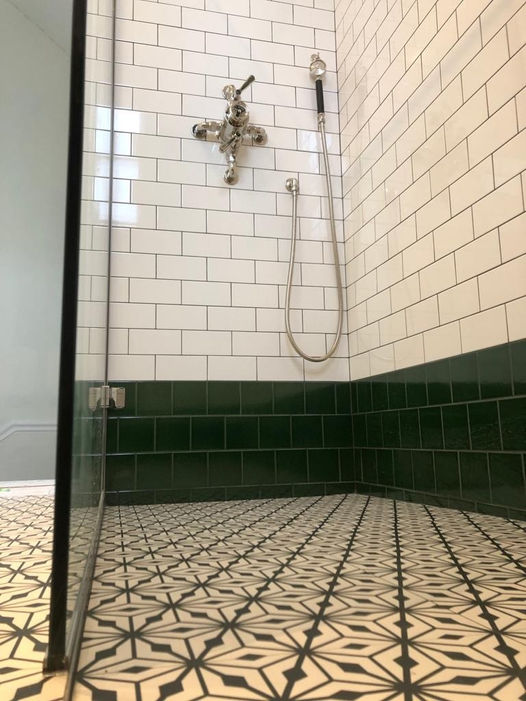 Traditional shower design with monochromatic pattern floor tiles and subway wall tiles.