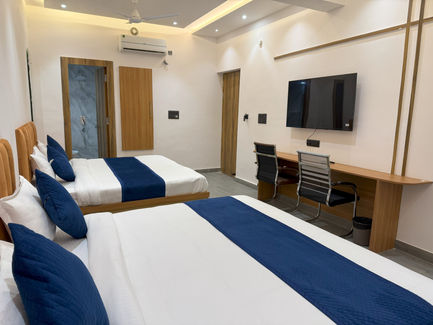 Spacious hotel room with two double beds, TV, and work desk