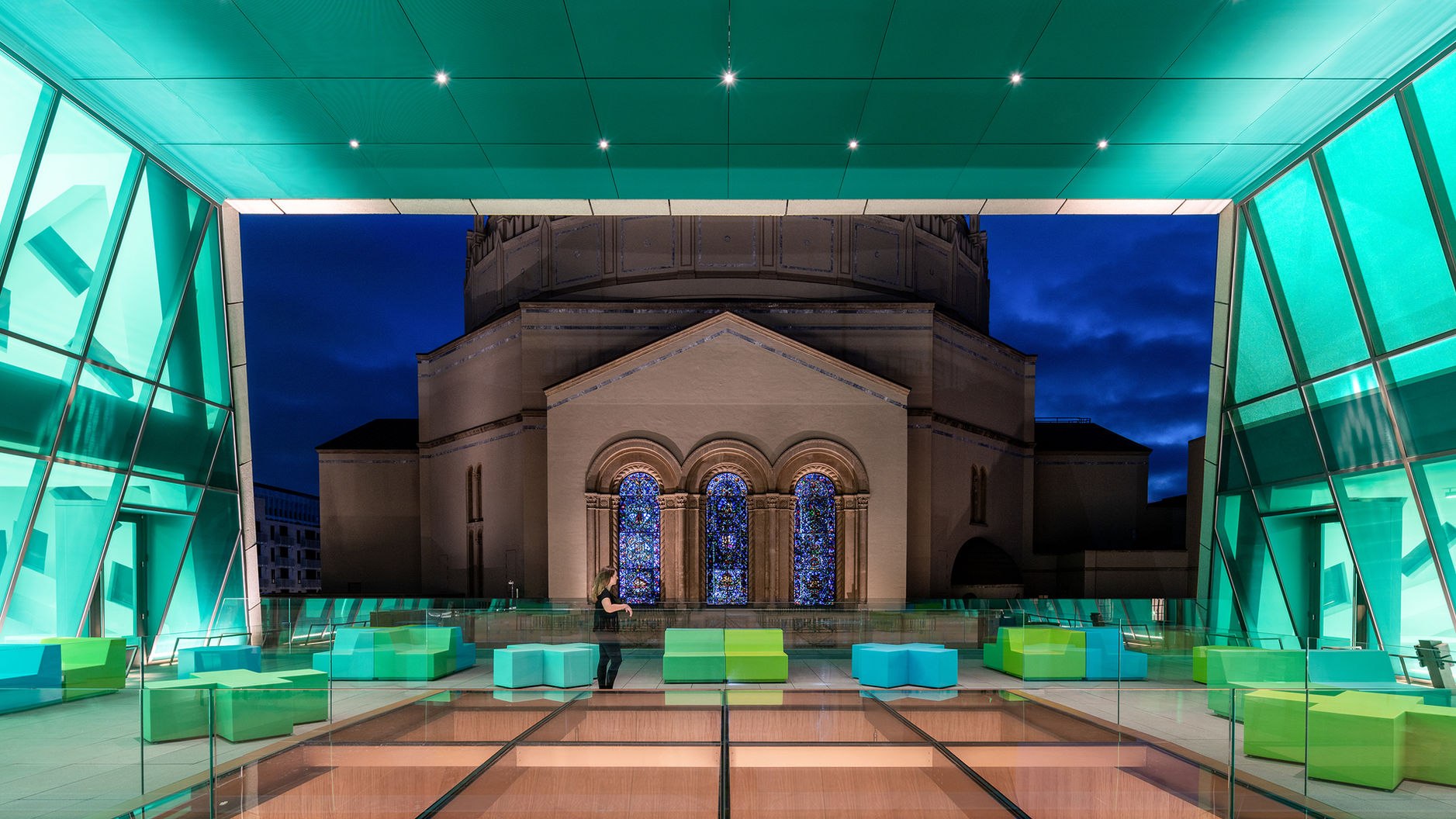 An interior view of a flexible room in the Audrey Irmas Pavilion at the Wilshire Boulevard Temple. The green room is set up with several lounge chairs, and the temple is visible outside the window.