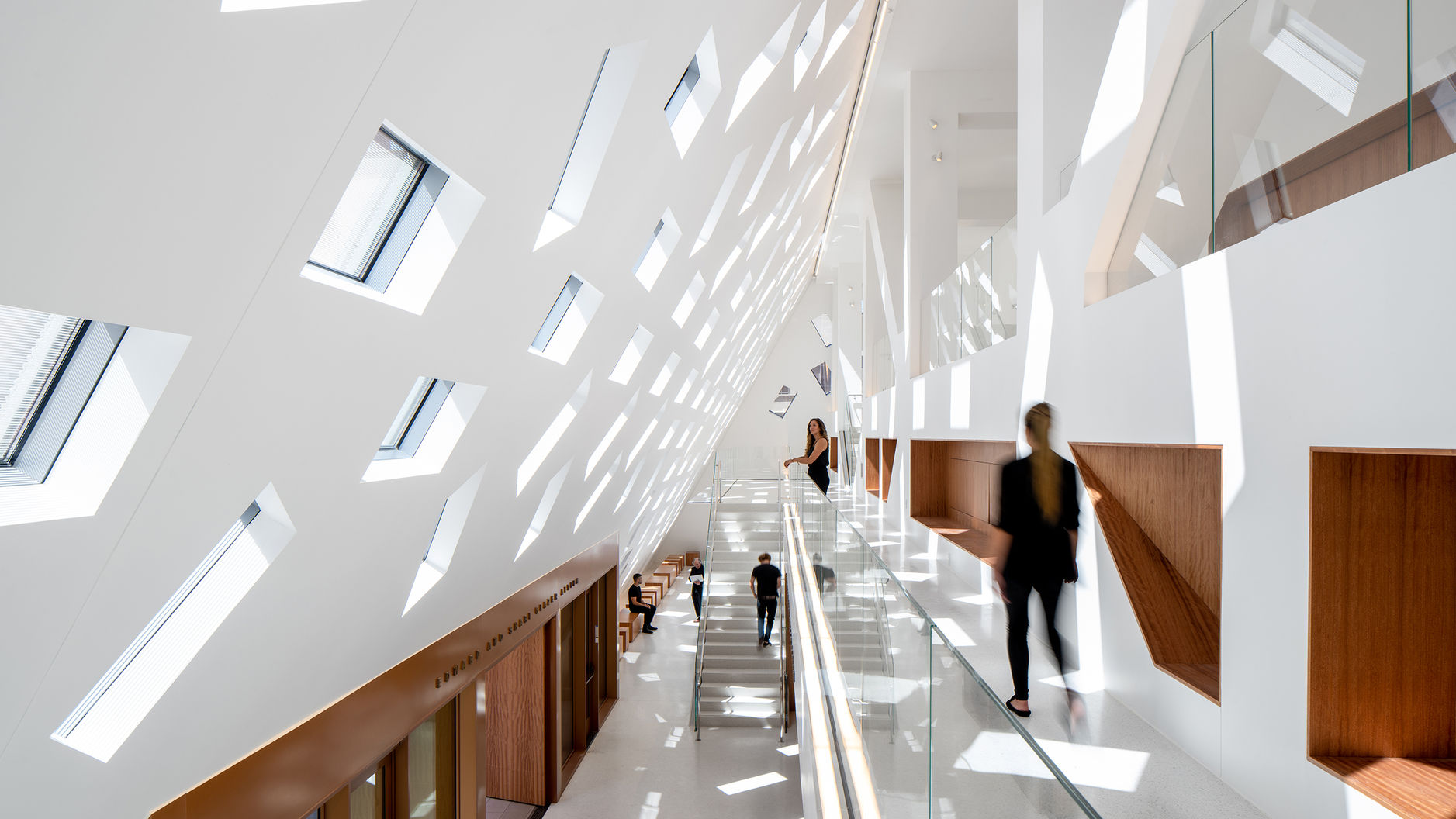 An interior view of the lobby of the Audrey Irmas Pavilion at the Wilshire Boulevard Temple during the afternoon. Several people are seen walking along the halls.